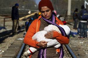 Κρατώντας ό,τι πολυτιμότερο έχει - Μια νεαρή μητέρα κρατά το μωρό της, περιμένοντας πάνω στις γραμμές του τρένου, στα βόρεια σύνορα της Ελλάδας (Ειδομένη, 30 Νοεμβρίου 2015)