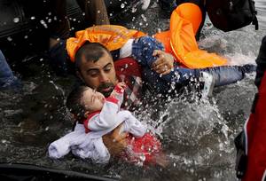 Νικώντας τα κύματα – Ο Σύρος πατέρας κρατά τα δυο του παιδιά, παλεύοντας να βγει στην ακτή (Λέσβος, 24 Σεπτεμβρίου 2015)