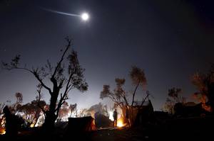 Το αστέρι της Βηθλεέμ - Ένας πρόσφυγας ζεσταίνεται στη φωτιά που έχει ανάψει κάτω από τον έναστρο ουρανό του Αιγαίου, δίπλα σε κέντρο καταγραφής προσφύγων, «μεταξύ θείας και ανθρώπινης δικαιοσύνης» (Λέσβος, 18 Νοεμβρίου 2015)