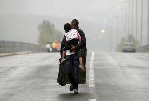 Σύρος πρόσφυγας φιλά την κόρη του καθώς περπατά μέσα στην καταιγίδα προς τα σύνορα της Ελλάδας με την ΠΓΔΜ, κοντά στο χωριό της Ειδομένης. 10 Σεπτεμβρίου, 2015.