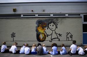 Εντυπωσιασμένοι οι μικροί μαθητές, θαυμάζουν τον γκράφιτι του Banksy που «στολίζει» το σχολείο τους.