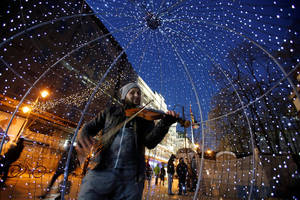 Ένας άνδρας παίζει βιολί στην κεντρική, στολισμένη πλατεία των Σκοπίων.