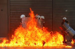 Φλόγες από τη ρίψη μολότοφ έχουν περικυκλώσει τους άνδρες των ΜΑΤ, στα επεισόδια που ξέσπασαν σε άλλη μία 24ωρη απεργία, στις 26 Σεπτεμβρίου του 2012, με δεκάδες χιλιάδες ανθρώπους να διαδηλώνουν κατά των νέων μέτρων λιτότητας