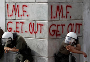 5 Μαΐου 2010 και δύο άνδρες των ΜΑΤ ξεκουράζονται σε μία γωνία, κατά τη διάρκεια άλλης μίας βίαιης διαδήλωσης κατά των μέτρων λιτότητας, ενώ ενδεικτικά για το ΔΝΤ είναι τα συνθήματα πίσω τους, γραμμένα με κόκκινη μπογιά