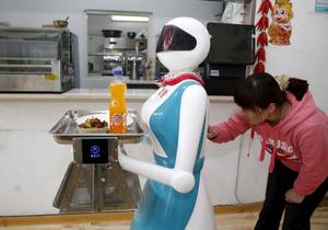 Μια γυναίκα δίνει οδηγίες σε ένα ρομπότ που εργάζεται ως σερβιτόρος, σε εστιατόριο στην Κίνα.