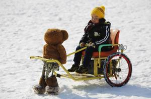 Ένα αγόρι κάνει βόλτες στο χιόνι, με τη βοήθεια ενός ρομπότ ντυμένο ως λούτρινο αρκουδάκι, το οποίο κινείται μόνο προς τα εμπρός , μετακινώντας τα πόδια του. Η φωτογραφία τραβήχτηκε στο πάρκο Taoranting στο Πεκίνο .