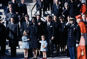 1963, Ουάσινγκτον. Η Τζάκι Κένεντι, χήρα του δολοφονηθέντος Προέδρου Τζον Φ. Κένεντι, μαζί με τα παιδιά της, έξω από την εκκλησία του Αγίου Ματθαίου στην Ουάσινγκτον, μετά την κηδεία του Κένεντι. Πίσω της στέκονται οι αδελφοί του, Έντουαρντ και Μπομπ.