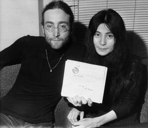 1969, Λονδίνο. Ο Τζον Λένον και η σύζυγός του, Γιόκο Όνο, στα γραφεία της Apple Records, δείχνουν μια επιστολή που έγραψε ο Λένον στον Πρωθυπουργό της Βρετανίας Χάρολντ Ουίλσον. Η επιστολή εξηγεί τους λόγους για τους οποίους ο Λένον επέστρεψε το μετάλλιο 