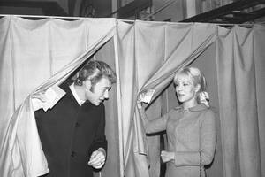 1965, Νεϊγί. Οι τραγουδιστές Τζόνι Χάλιντεϊ και Σιλβί Βαρτάν, ζευγάρι στη ζωή, ψηφίζουν σε διπλανά παραβάν, για τις προεδρικές εκλογές, στο Δημαρχείο του Νεϊγί, όπου μένουν.