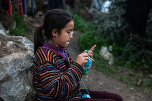 Ένα κορίτσι πλέκει καθισμένο σε μία πέτρα. Γύρω της δεκάδες εστίες μικροβίων από σκουπίδια αποτελούν κίνδυνο για μικρούς και μεγάλους.