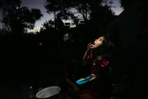 Ένα κορίτσι από το Αφγανιστάν τρώει βραδινό, υπό το φως ενός φακού