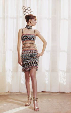 15 Φεβρουαρίου 1967. Ένα κοντό βραδινό φόρεμα με  κεντήματα και πέρλες. Ξύλινα σκουλαρίκια. Κολάρο ασορτί με τα κεντήματα, χρυσό βραχιόλι, χρυσά δερμάτινα παπούτσια.  Yves St. Laurent, Παρίσι.