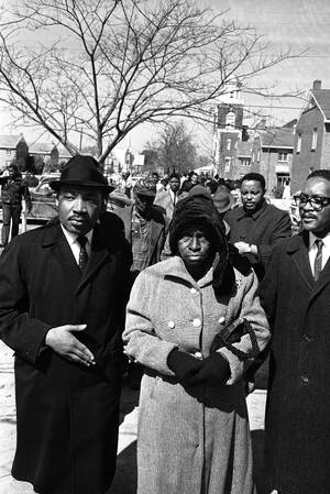 1965
Ο Μάρτιν Λούθερ Κινγκ φεύγει από μια εκκλησία στην Αλαμπάμα, αφού έχει παρακολουθήσει τη λειτουργία. Κατευθύνεται στο δικαστήριο για να παραστεί στη δίκη Αφροαμερικανών που συνελήφθησαν κατά τη διάρκεια διαδηλώσεων υπέρ ου δικαιώματος των μαύρων να 