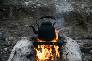 Ένας βραστήρας νερού, κατάμαυρος από την φωτιά, πάνω σε μία αυτοσχέδια εστία.
