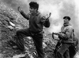 1957
Άγγλος στρατιώτης συλλαμβάνει ένα μέλος της ΕΟΚΑ. Στο καταφύγιο στο οποίο κρυβόταν, στο όρος Τρόοδος, βρισκόταν και ο υπαρχηγός της ΕΟΚΑ, Γρηγόρης Αυξεντίου, τον οποίο οι Άγγλοι είχαν επικηρύξει. Ο Αυξεντίου αρνήθηκε να παραδοθεί και σκοτώθηκε όταν 